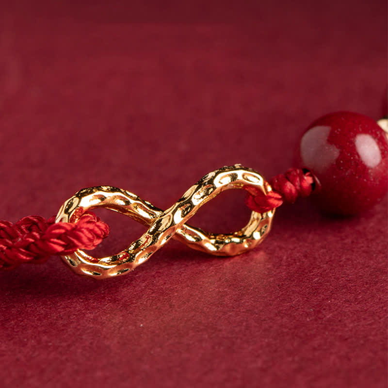 Gold infinity symbol bracelet with red cord on a red background