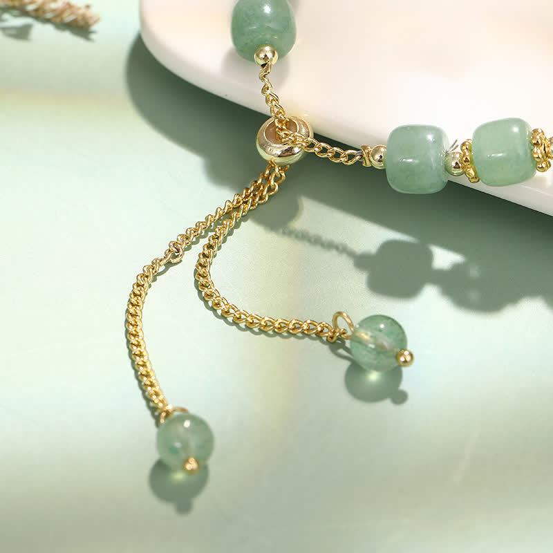 Bracelet with green beads and gold chain on a light background