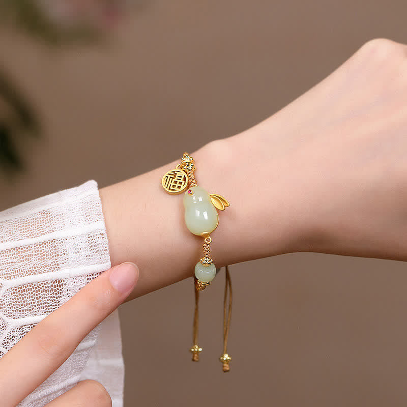 Bracelet with green bead and gold accents on a wrist against a neutral background