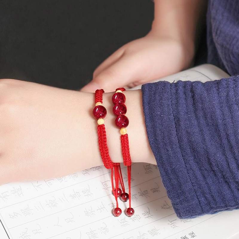 Red beaded bracelet on a wrist with a dark background