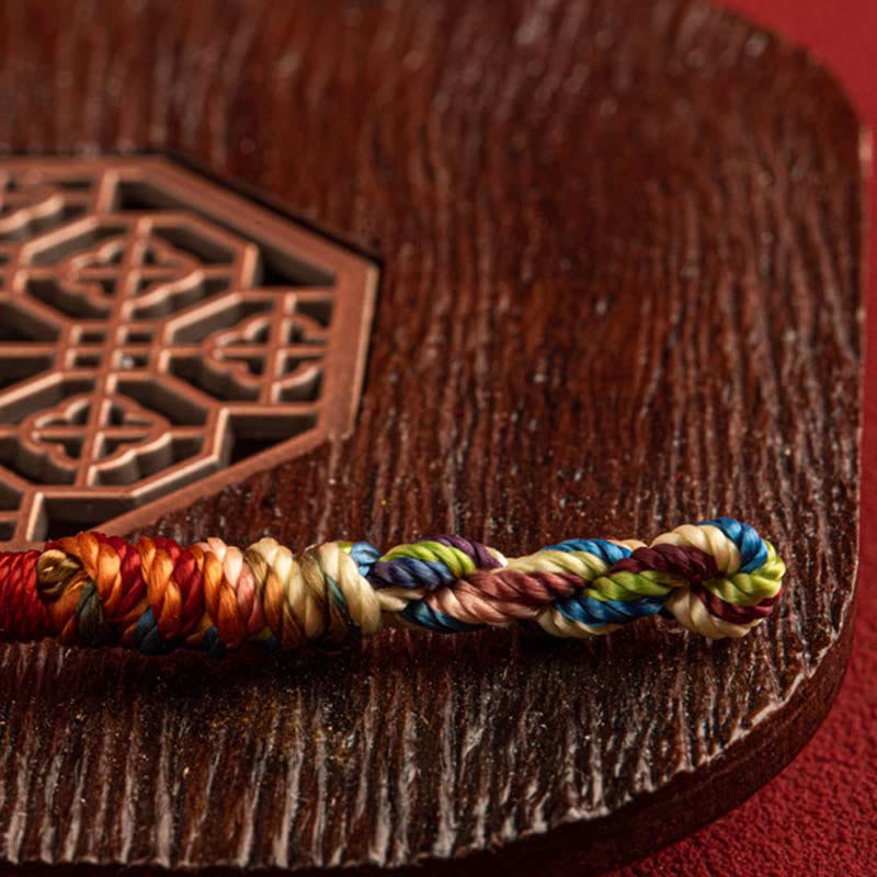 Detailed view of the Five-Color Longevity Blessing Bracelet resting on wooden surface – handcrafted symbolic energy jewelry.