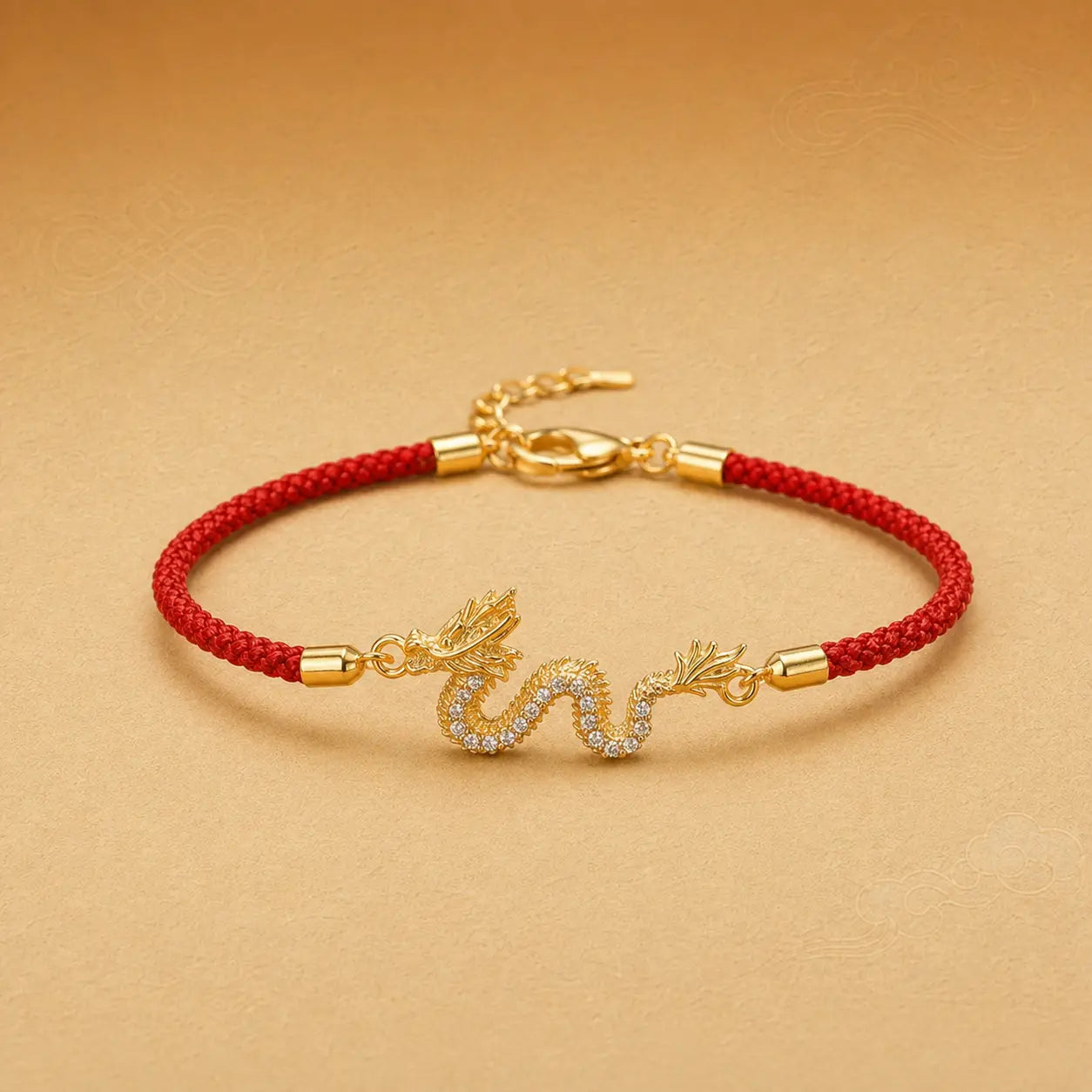 Gold bracelet with a red cord and dragon charm on a beige background