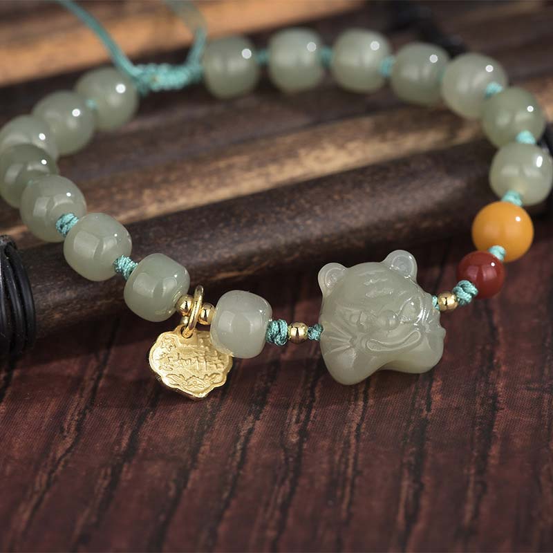 Necklace with jade beads and tigers' head charm on a wooden surface
