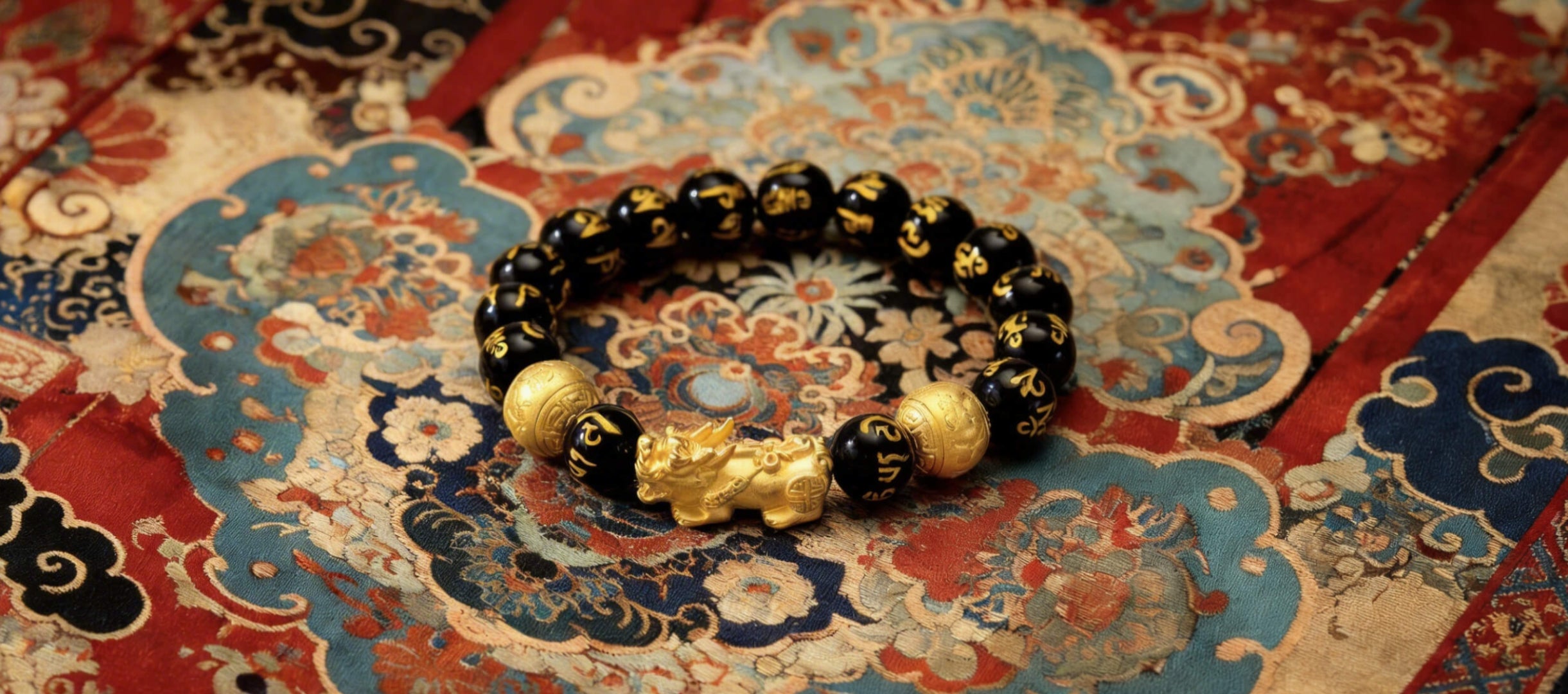 Bracelet with gold and black beads on a decorative fabric background