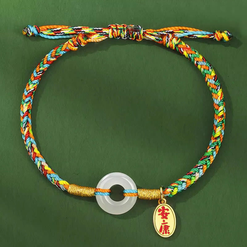 Colorful braided bracelet with a gold ring and pendant on a green background