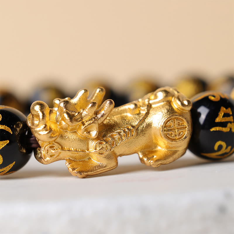 Close-up view of the golden PiXiu charm on obsidian beads