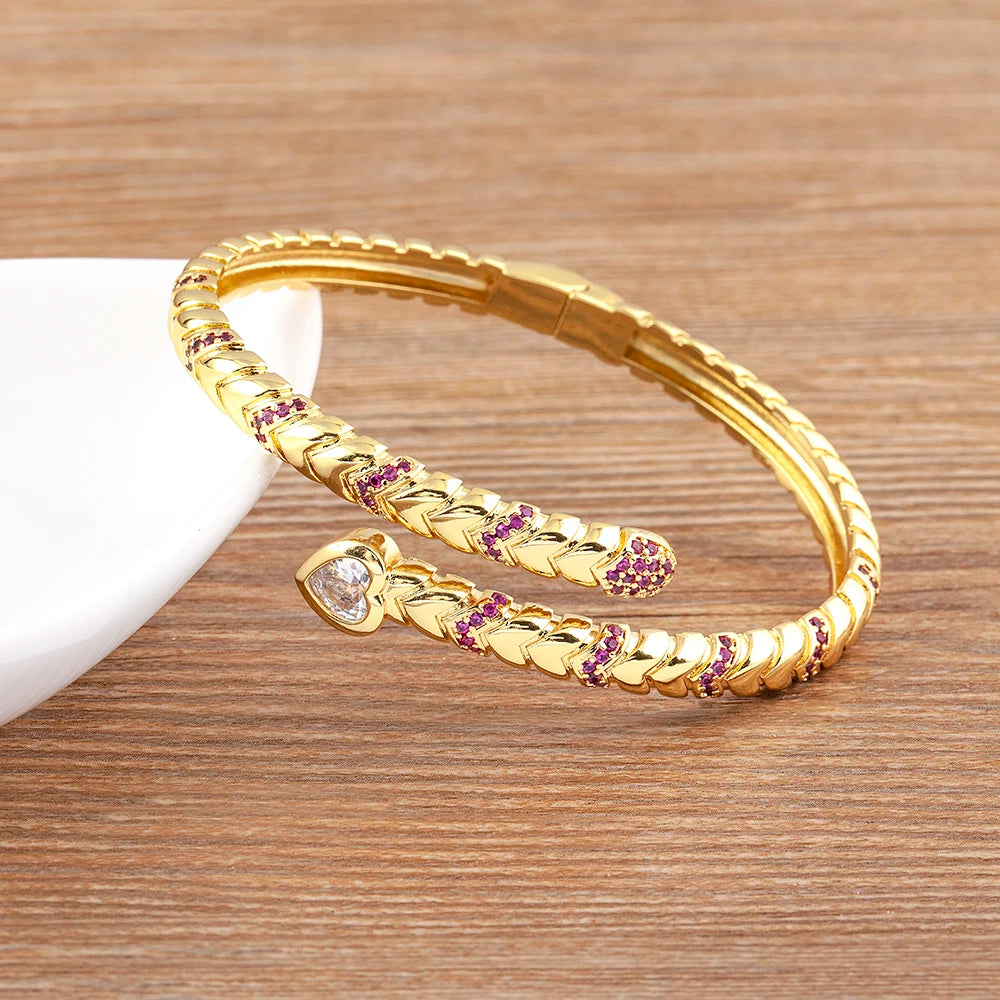 Coiled Grace Snake Zircon Gold Cuff Bracelet displayed on wooden surface