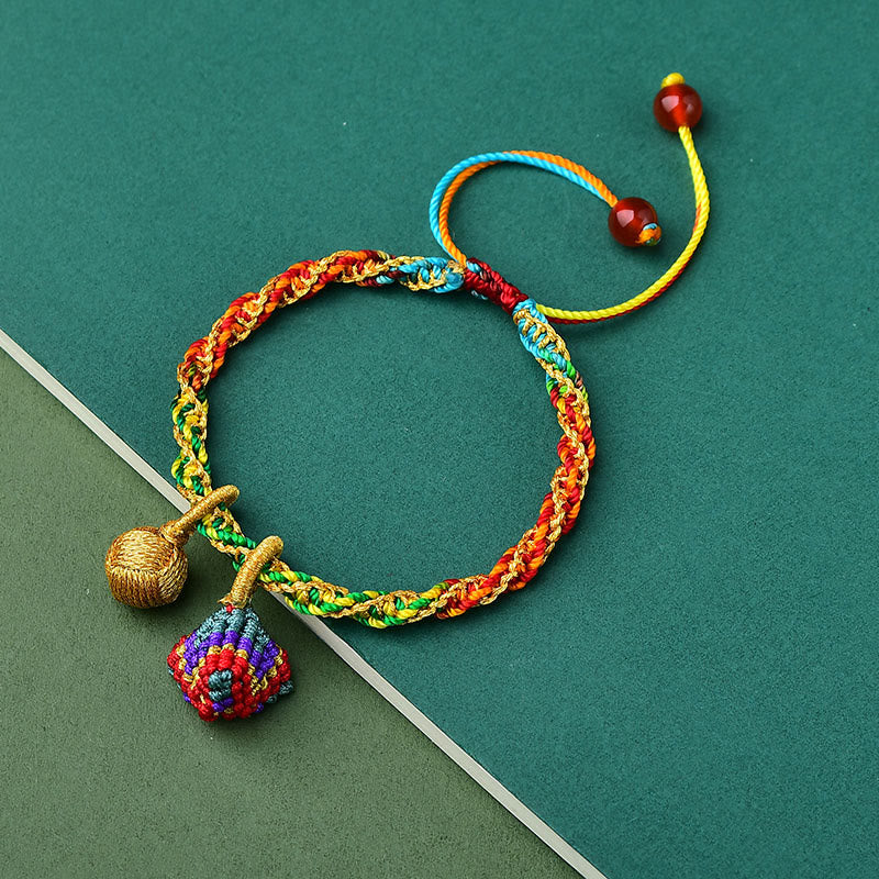 Colorful braided bracelet with decorative elements on a green background