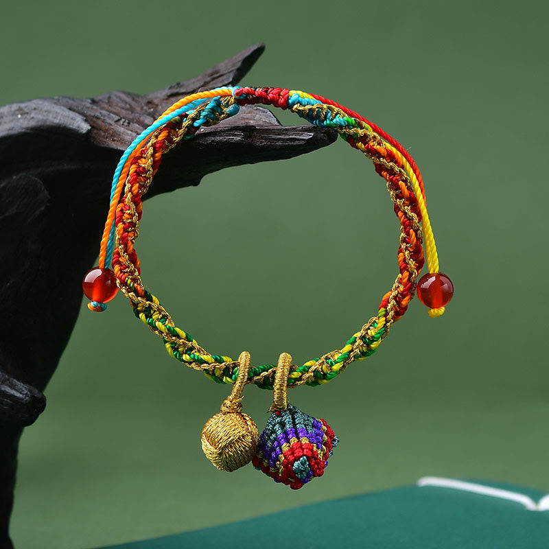 Colorful braided bracelet with gold beads on a dark surface