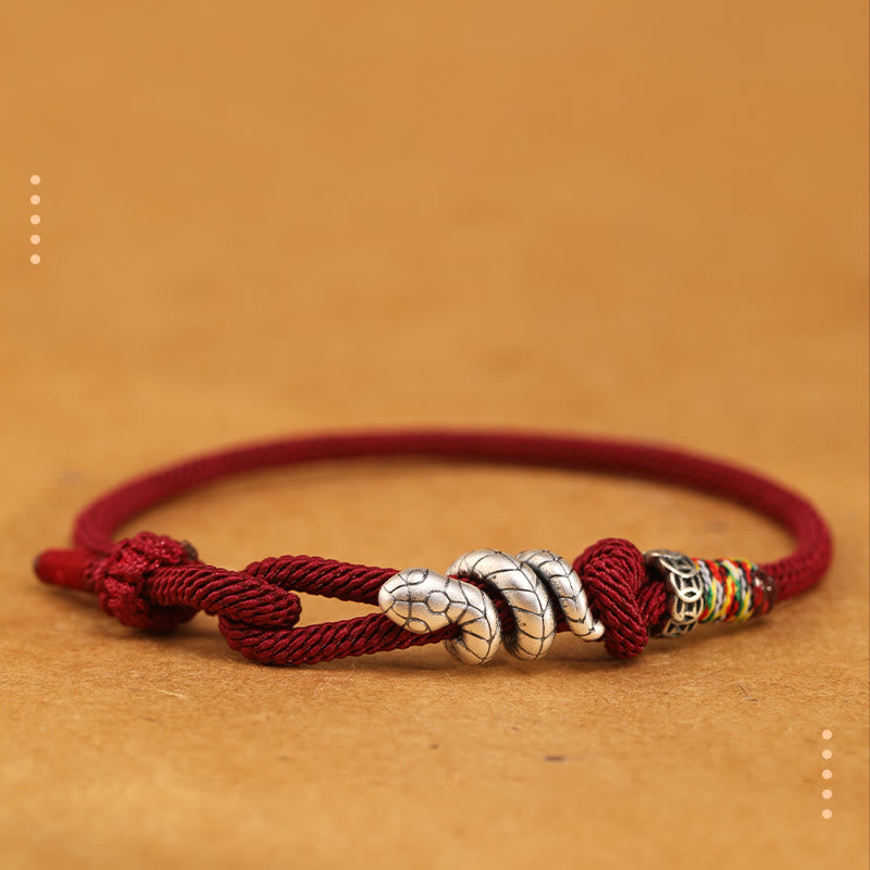 Bracelet with red cord and silver beads on a brown background
