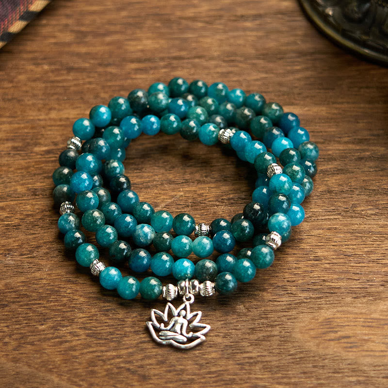 Teal beaded bracelet with silver lotus charm on a wooden surface