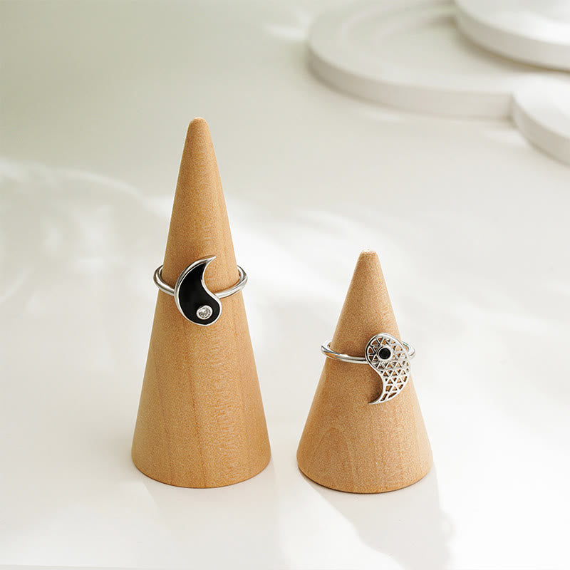 Two silver rings on wooden cone stands against a white background