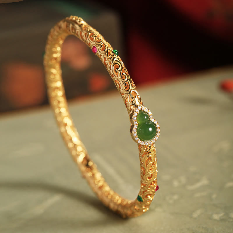 Crafted with traditional gold filigree technique, the bracelet features intricate auspicious cloud patterns and a central natural Hetian碧玉 gourd pendant, symbolizing "blessings and prosperity". The fusion of gold and jade exudes both elegance and profound Eastern cultural meaning, making it a perfect choice for daily wear or collection.