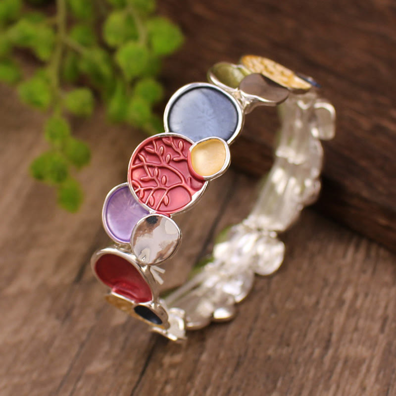 Decorative bracelet with colorful circular elements on a wooden surface