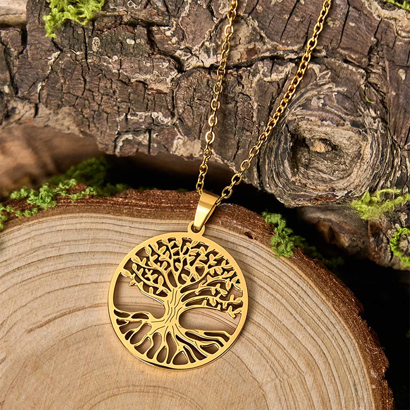 Gold tree-shaped pendant necklace on a wooden surface with a natural background