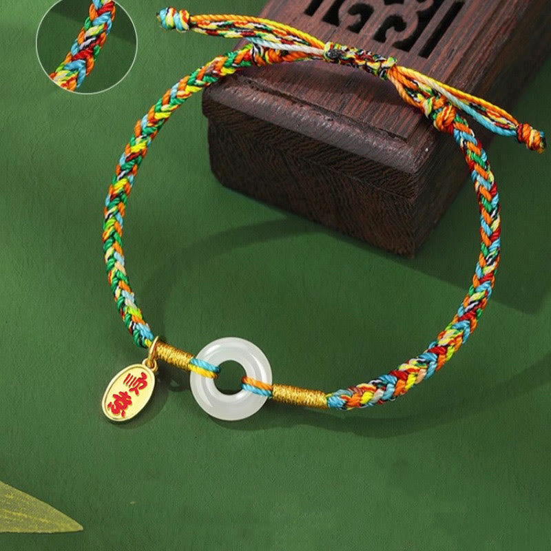 Colorful braided bracelet with a white stone charm and red tag on a green background