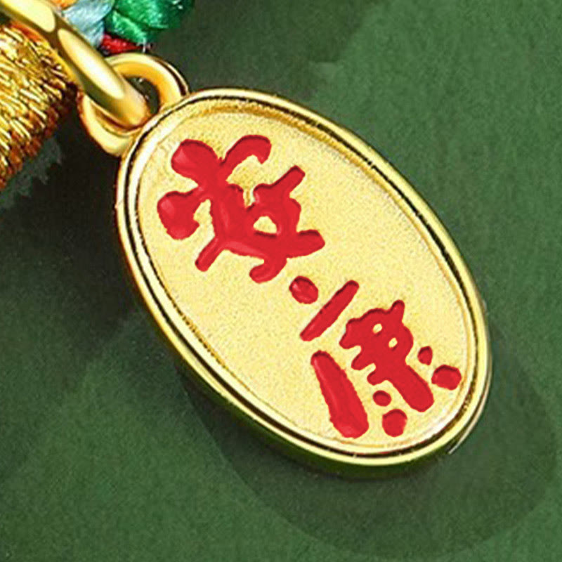Gold pendant with red Chinese characters on a green background