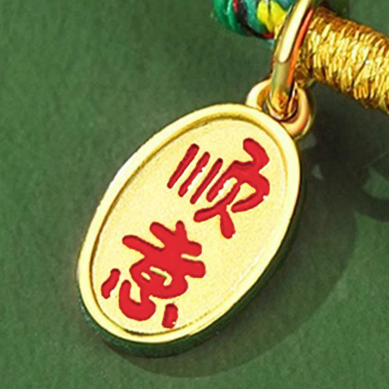 Gold pendant with red Chinese characters on a green background