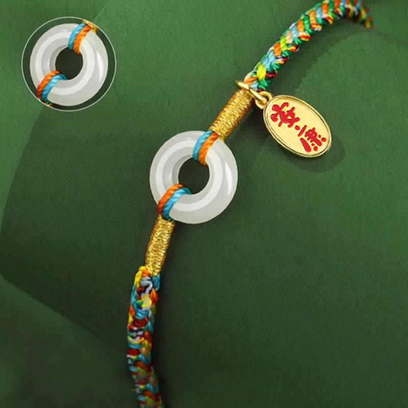 Colorful braided cord with a white circular charm and gold tag on a green background