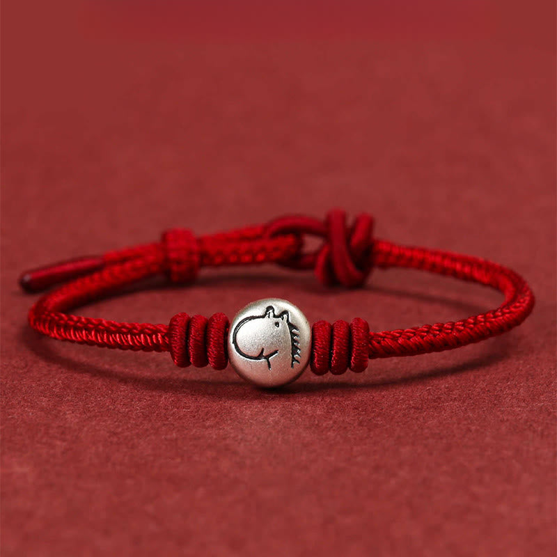 Red bracelet with a silver charm on a red background