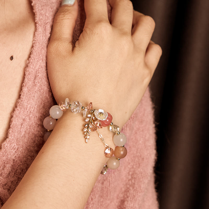 Close-up of a hand wearing a beaded bracelet with a soft pink background