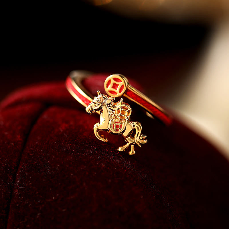 Gold bracelet with a horse charm on a red fabric background
