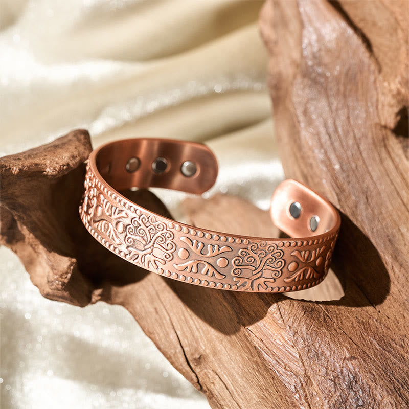 Copper bracelet with intricate designs on a wooden surface