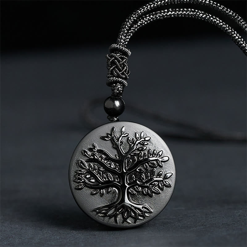 Silver pendant with tree design on a dark background