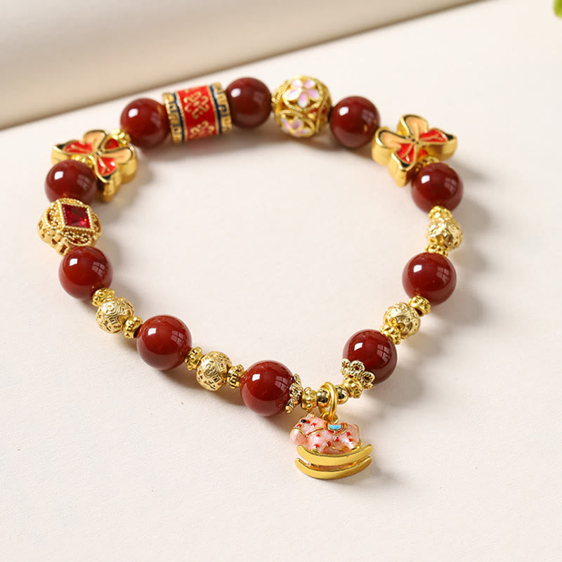 Bracelet with red beads and gold accents on a white surface