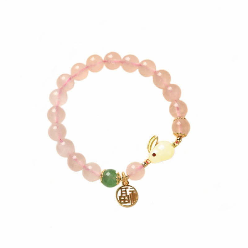 Pink beaded bracelet with a gold charm on a white background
