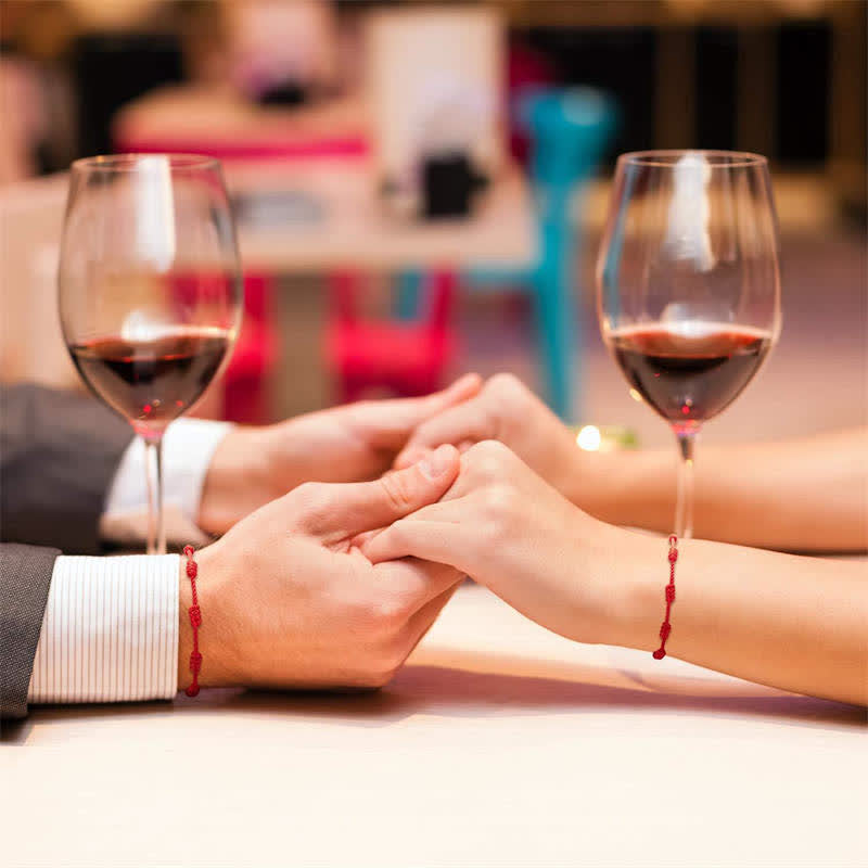 Two people holding hands with wine glasses on a blurred background