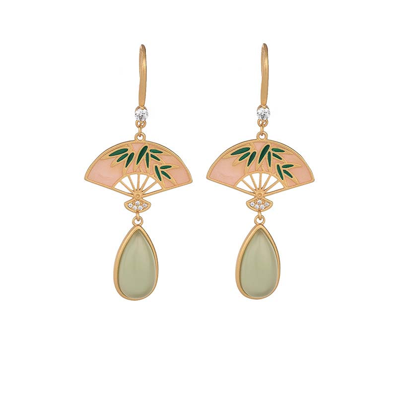 Pair of earrings with gold frames, green leaves, and teardrop-shaped stones on a white background