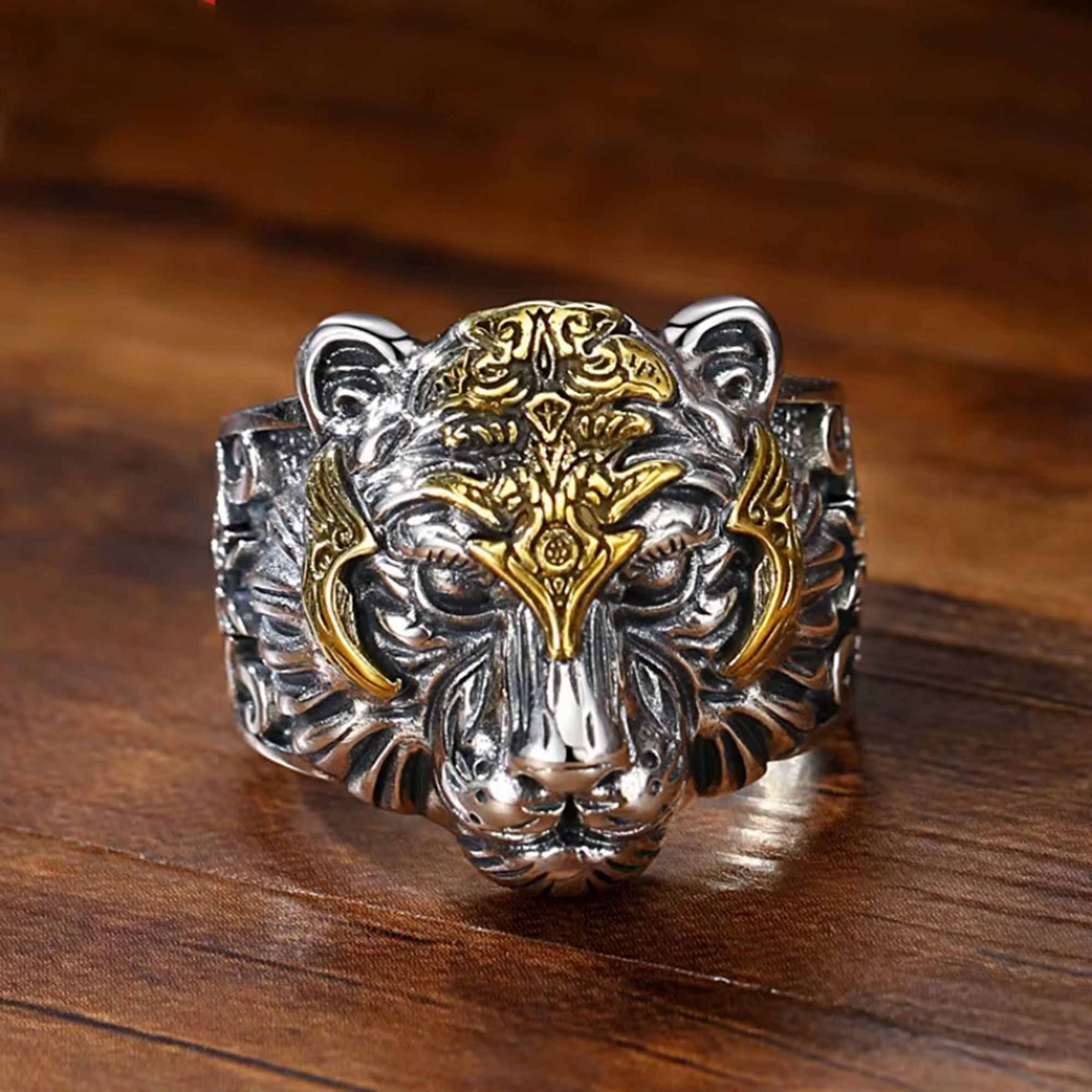Silver and gold tiger head ring on a wooden surface
