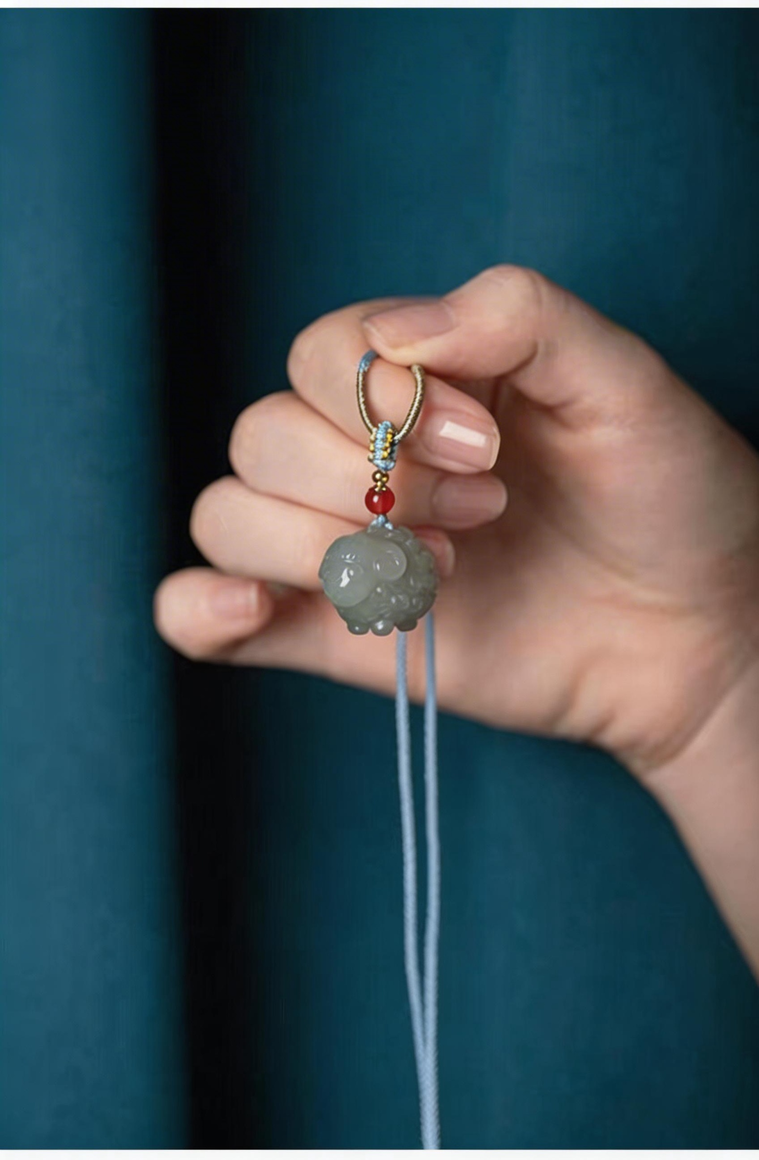 Hand holding a decorative pendant with beads against a dark blue background