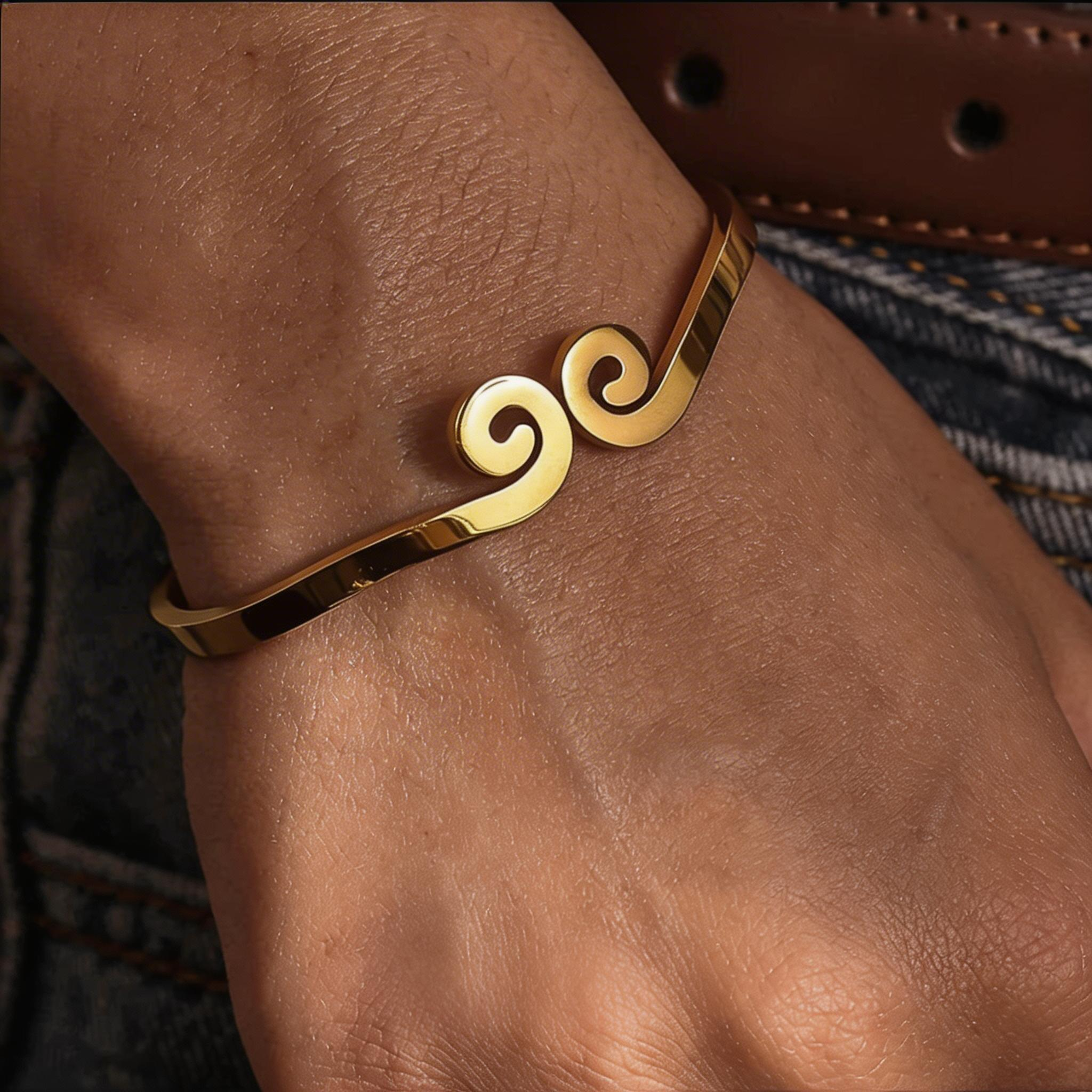 Gold bracelet with spiral design on a wrist against a denim background
