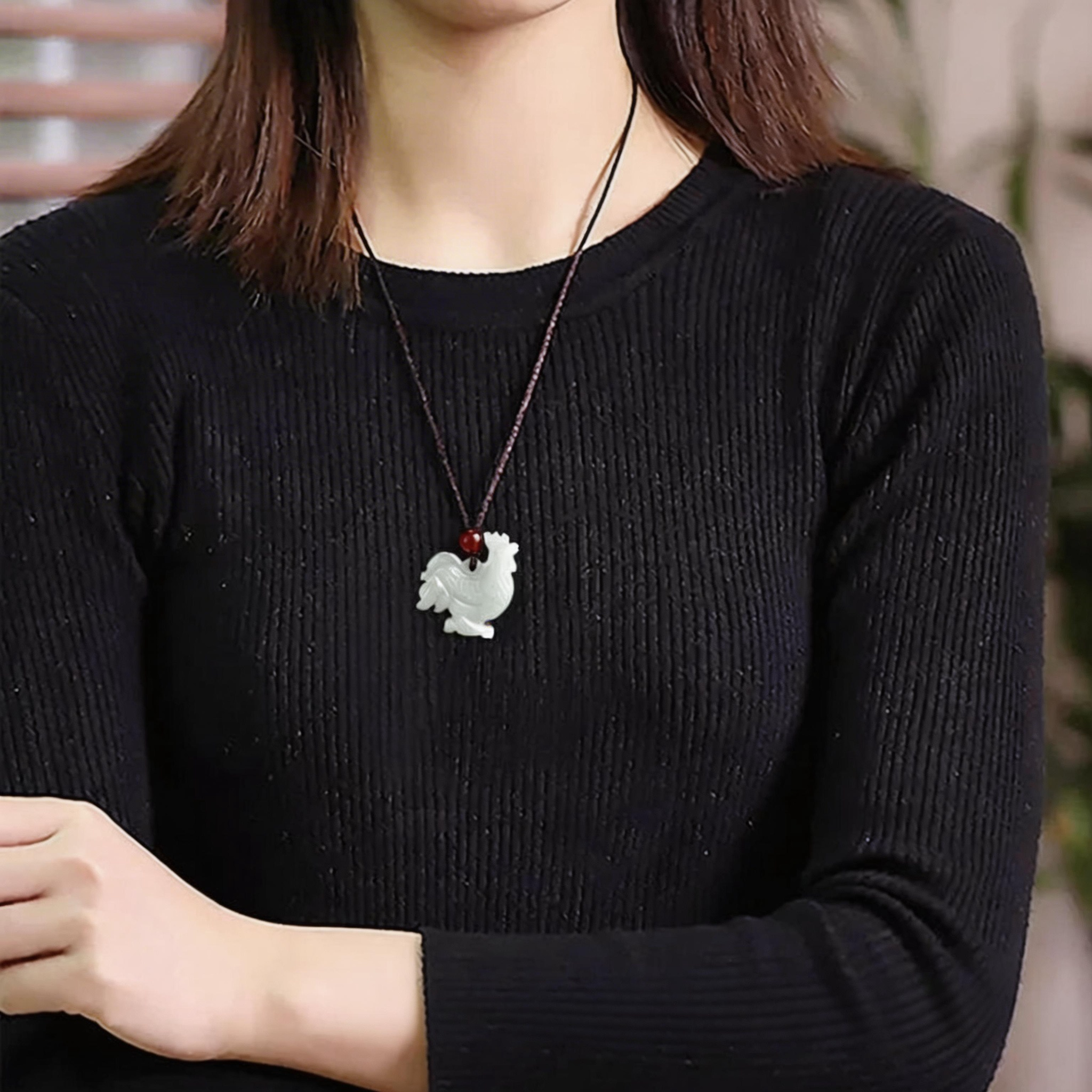Person wearing a black sweater with a necklace featuring a dog pendant.