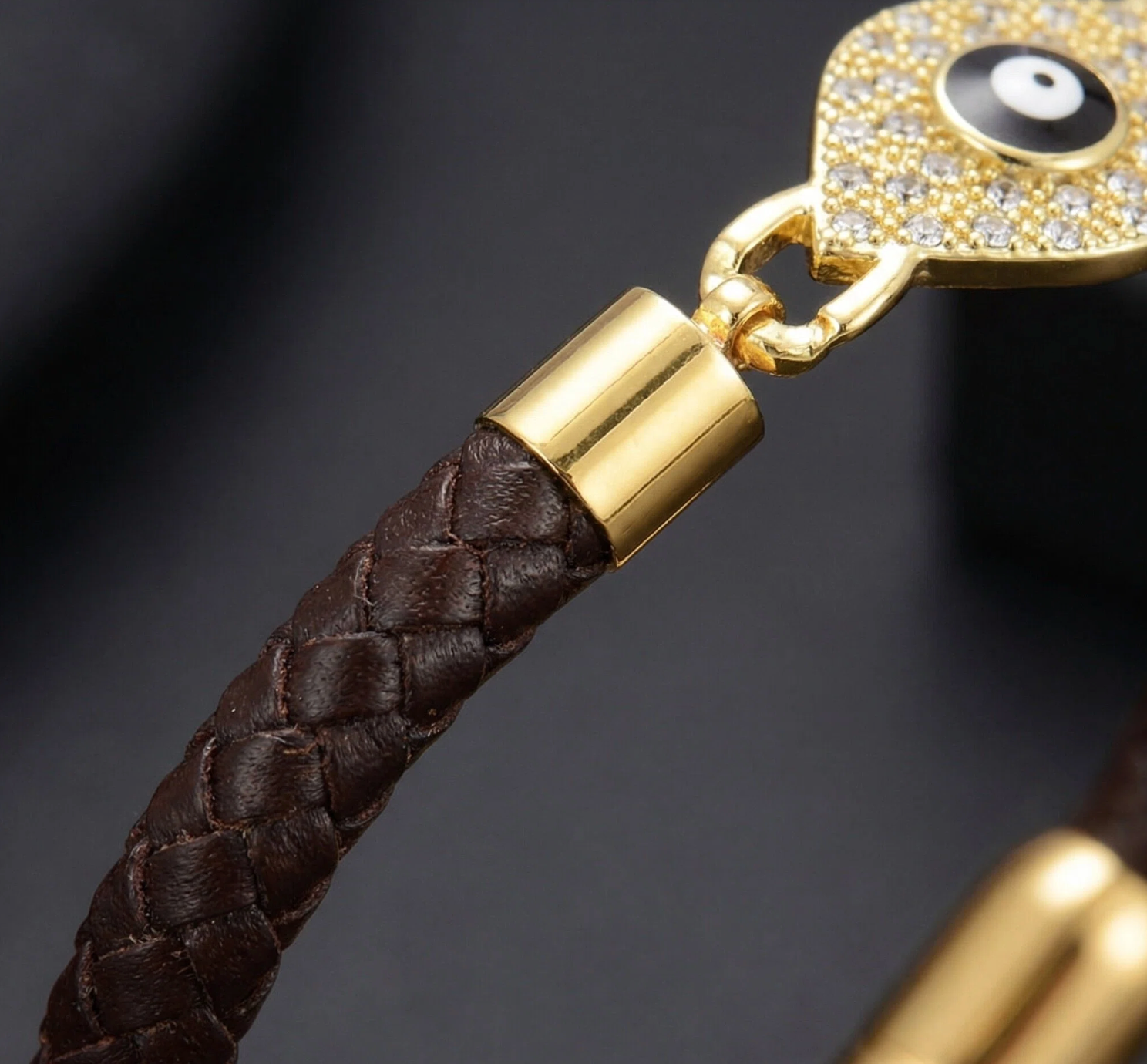 Bracelet with brown leather strap and gold clasp on a dark background
