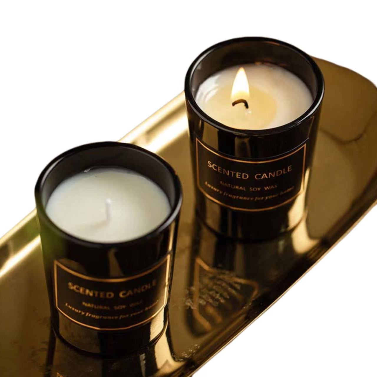Two scented candles in black tins on a reflective surface