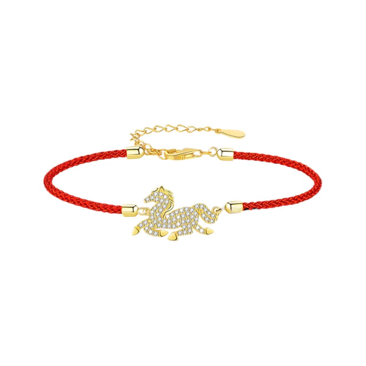Bracelet with gold horse charm on red cord against a white background