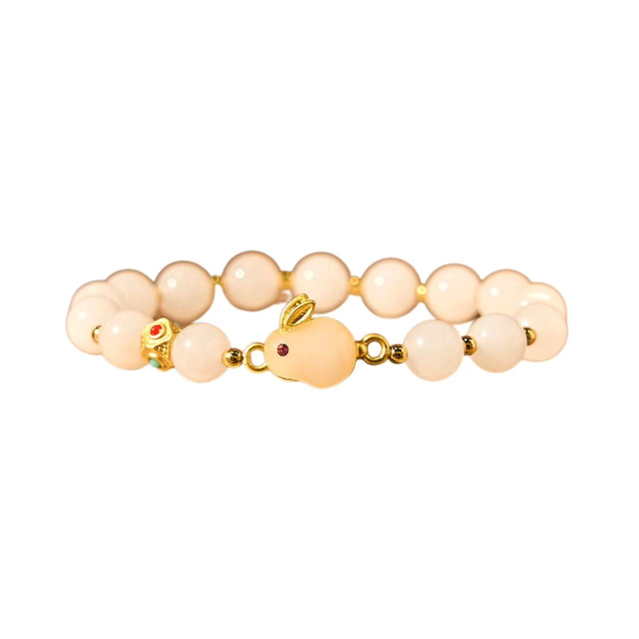 Beige beaded bracelet with gold accents and red gemstones on a white background