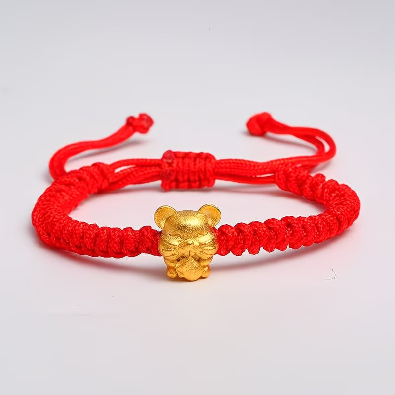 Red bracelet with a gold charm on a light gray background
