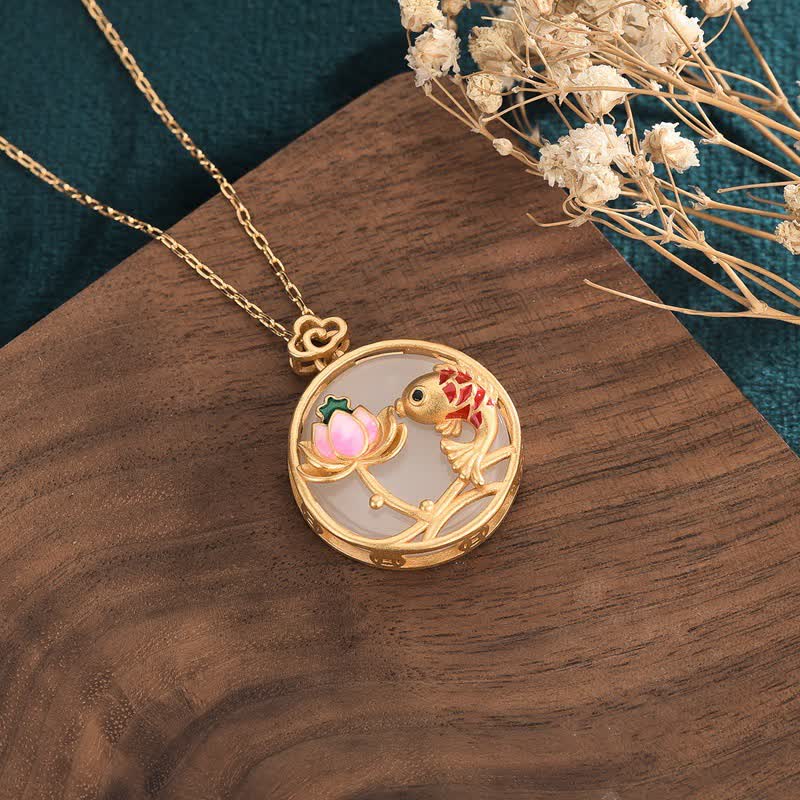 Gold necklace with a detailed pendant on a wooden surface with dried flowers.