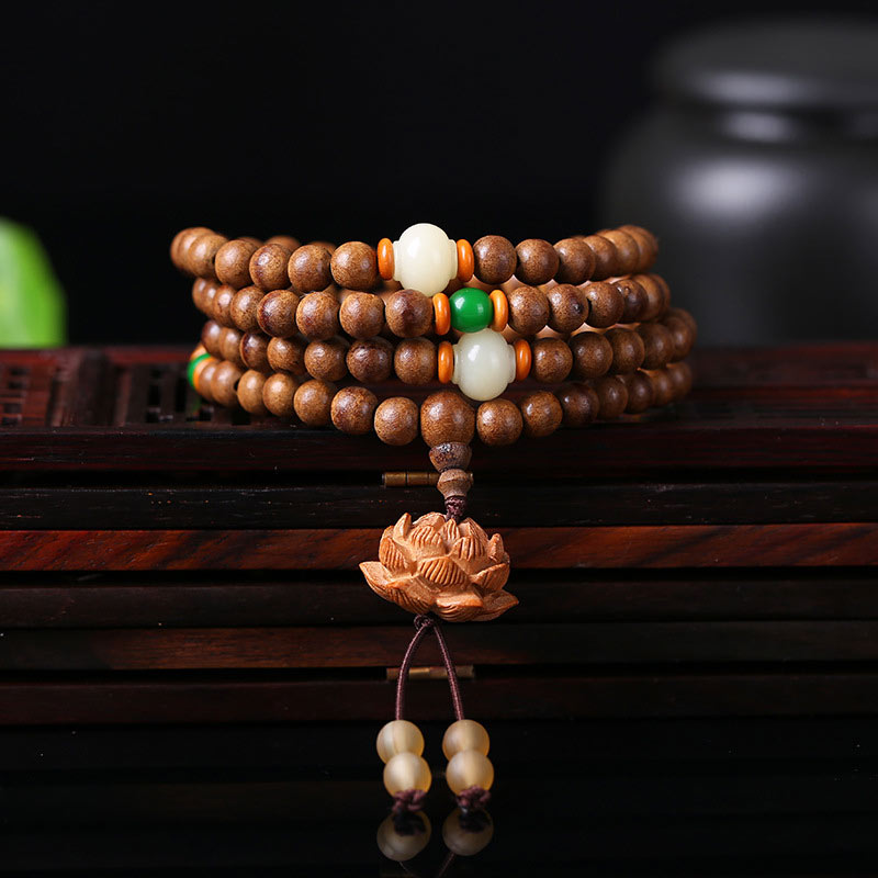 Wooden beaded bracelet with a lotus flower charm on a dark background