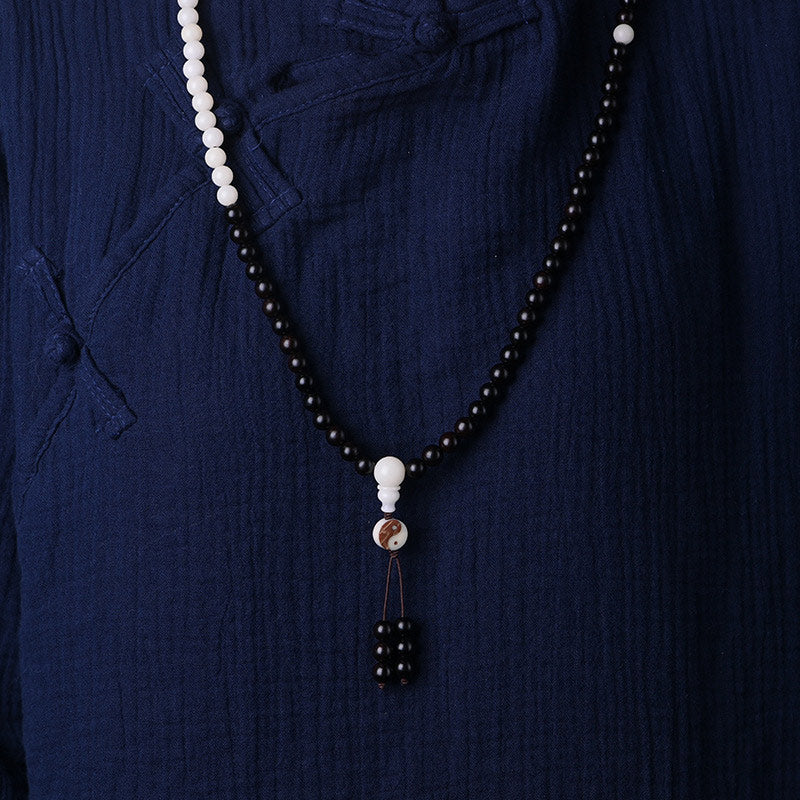 Necklace with black and white beads on a dark blue fabric background