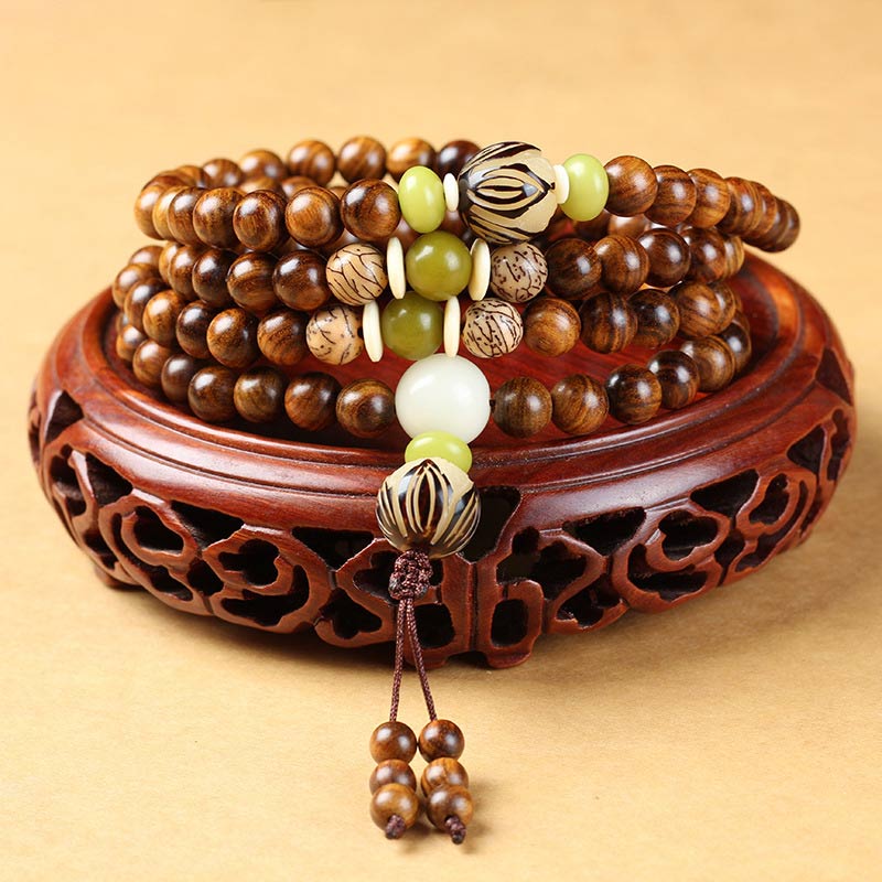 Wooden beaded bracelet with green and white accents on a decorative wooden stand.