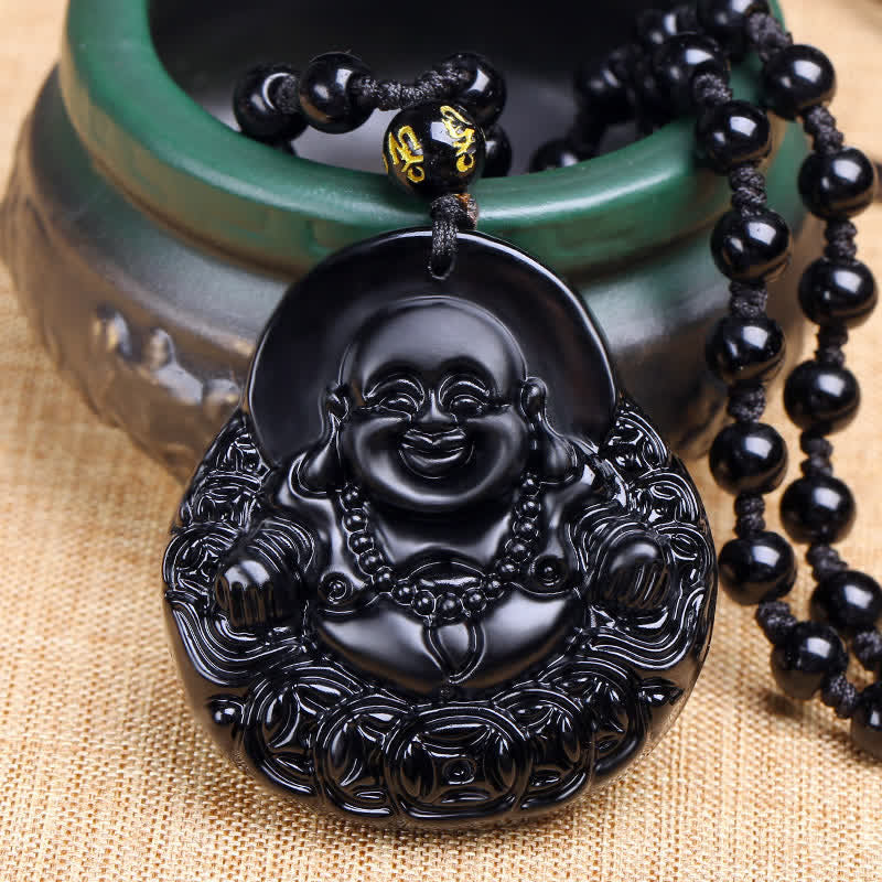 Black Buddha pendant with beads on a textured surface