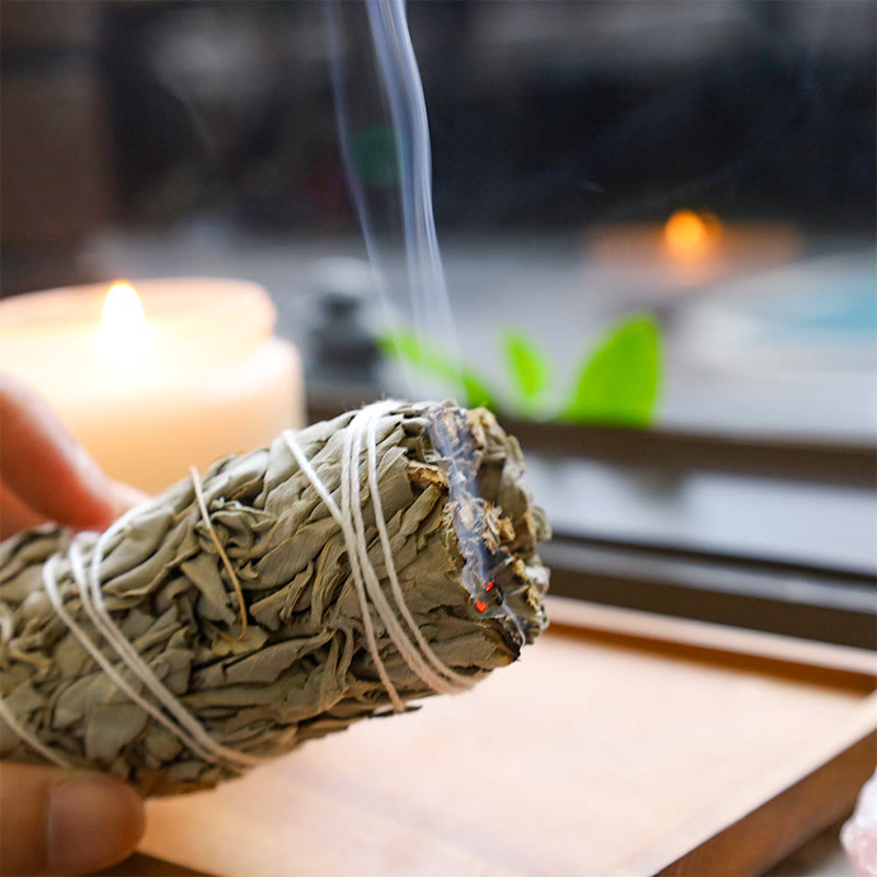 Bundled sage smudge stick with smoke against a blurred background