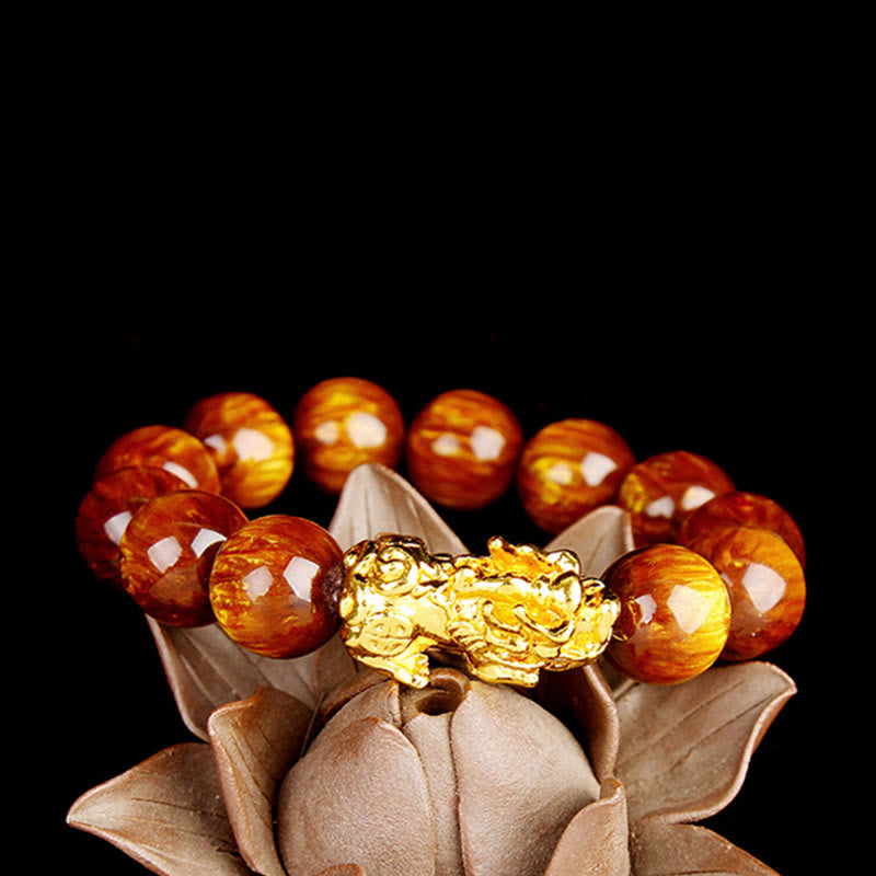 Bracelet with amber beads and a gold charm on a decorative leaf