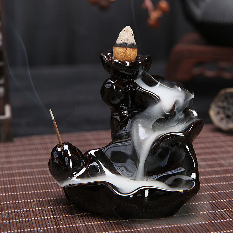 Black and white ceramic incense burner with incense sticks on a woven mat.