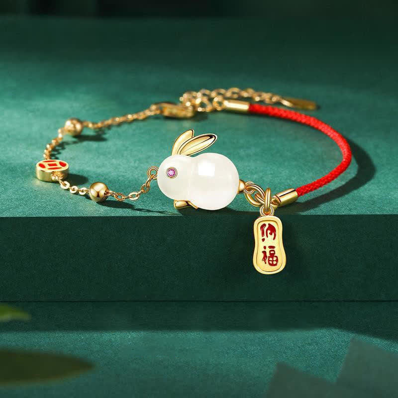 Bracelet with rabbit charm and red string on a green background